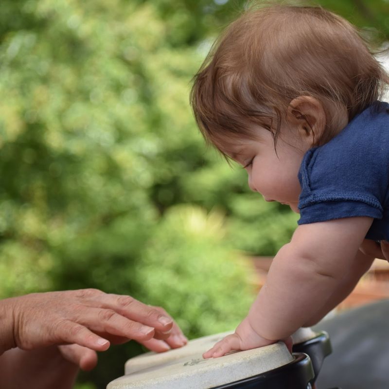 A toddler playing a hand drum